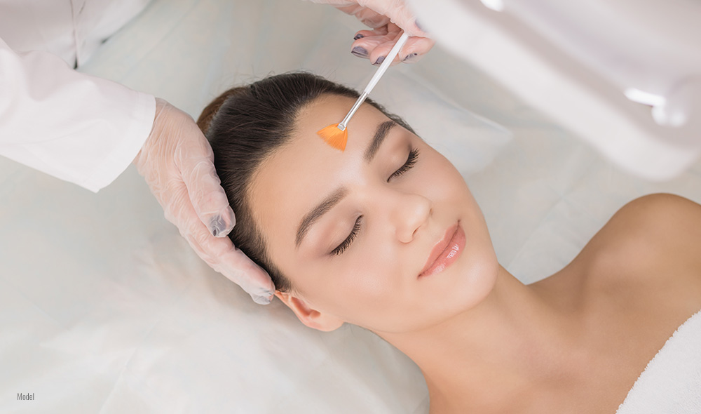 Doctor applying chemical peel on a female